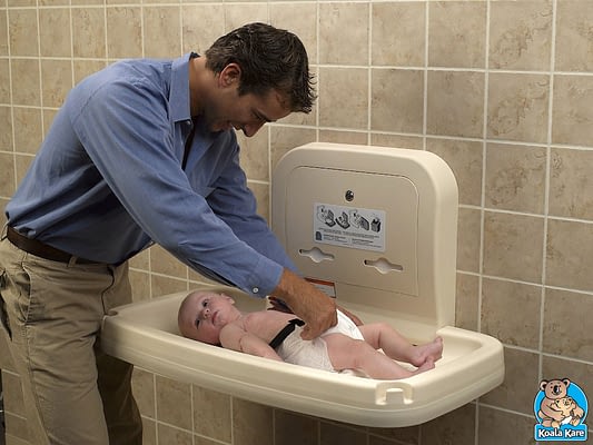 Man Pretending to Change Baby's Diaper on Beige Changing Table
